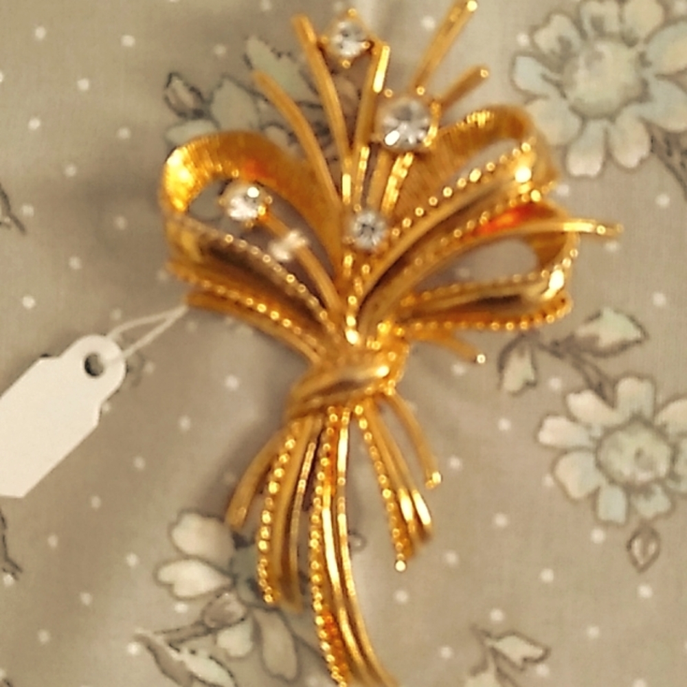 Oggie design brooch with gold ribbon with burst of crystal gems shooting out off